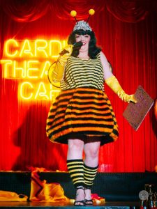 Female in black wig dressed as a bee with a furry skirt in yellow and black stripes